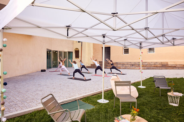 Gazebo Ecotent bianco 6x4m su gairdino davanti alla biblioteca di Bressanone utilizzato outdoor per corso di yoga rpara l'area relax dal sole