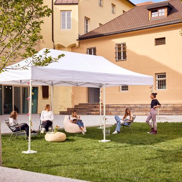 Der 6x3 m große Faltpavillon dient als Outdoor-Überdachung einer Bibliothek. Darunter sitzen Jugendliche.