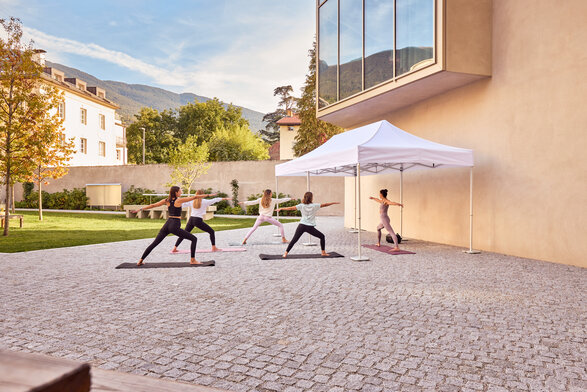 Gazebo Ecotent bianco 6x4m su gairdino davanti alla biblioteca di Bressanone utilizzato outdoor ripara dai raggi UV l'insegnante del corso di yoga