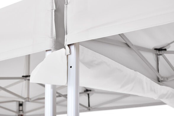 The rain gutter is mounted between two light grey folding gazebos.