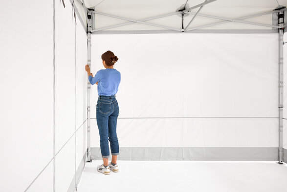 The woman assembles the 2 closed side walls on the folding gazebo.