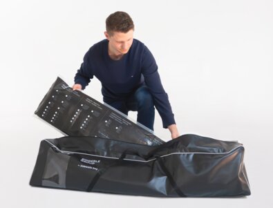 The man packs the folding gazebo side walls in the black side wall bag.