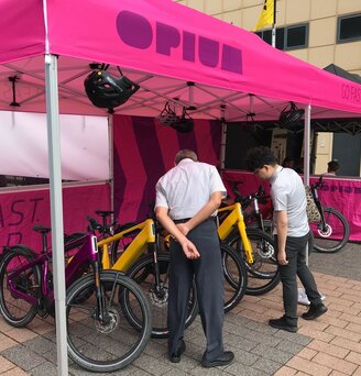 Gazebo pieghevole fuxia 6x3 personalizzato con logo Opium e diversi teli laterali all'Eurobike in Svizzera fa da stand delle biciclette mentre due uomini guardano.