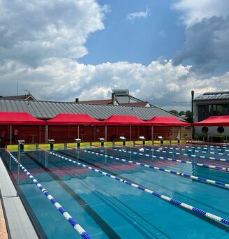 Cinque gazebo rossi 8x4 al bordo di una piscina olimpionica esterna