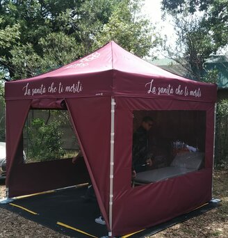 Gazebo 3x3 bordeaux personalizzato con scritta la sanità che ti meriti con pavimento nero in PVC, telo laterale chiuso, telo laterale con porta e teli laterali con finestre panoramiche in un bosco. Ecotent