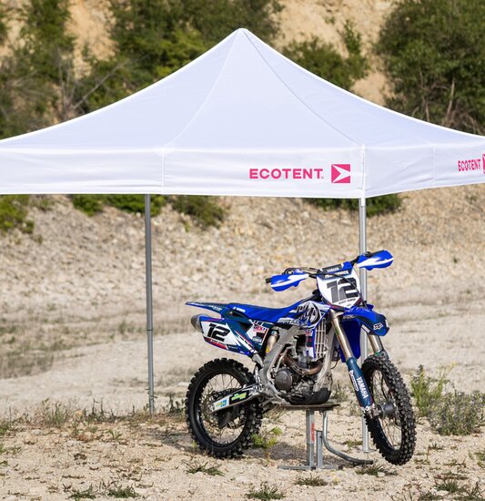 Gazebo bianco 3x3 m con logo Ecotent fuxia copre una moto da motocross blu nel deserto